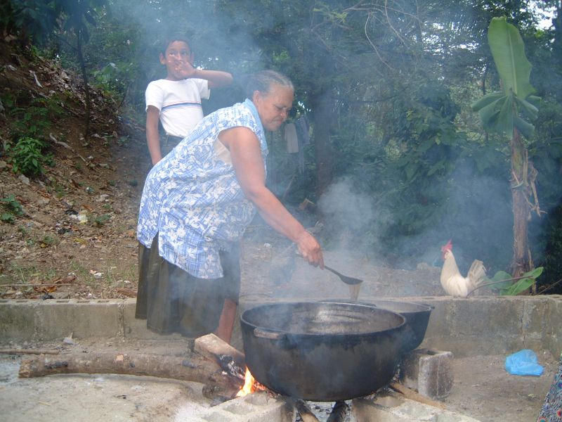 Cooking large pans of sancocho over an open fire for a birthday celebration.